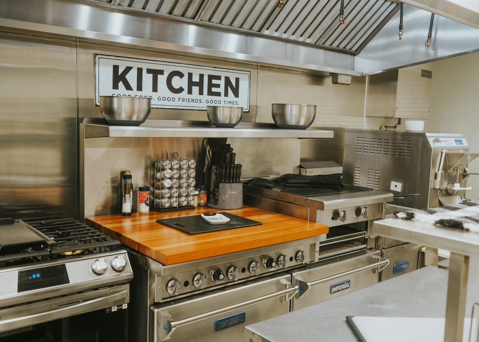 Modern commercial kitchen featuring stainless steel appliances, wooden countertop, cooking range, and organized utensils, emphasizing efficient food preparation and safety for plumbing services.