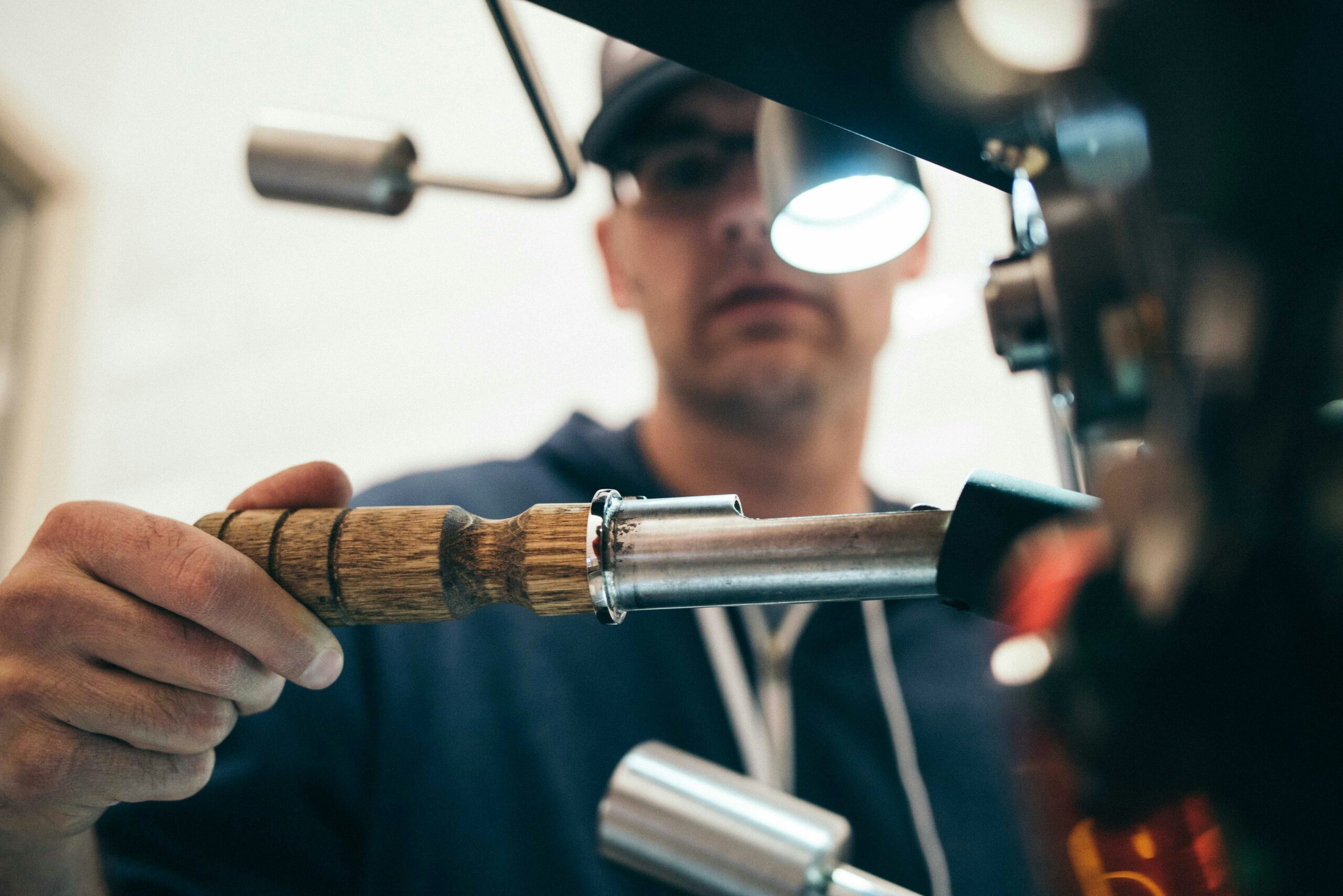 Man holding a plumbing tool with a wooden handle, focused on equipment, emphasizing professional plumbing services and emergency repairs.