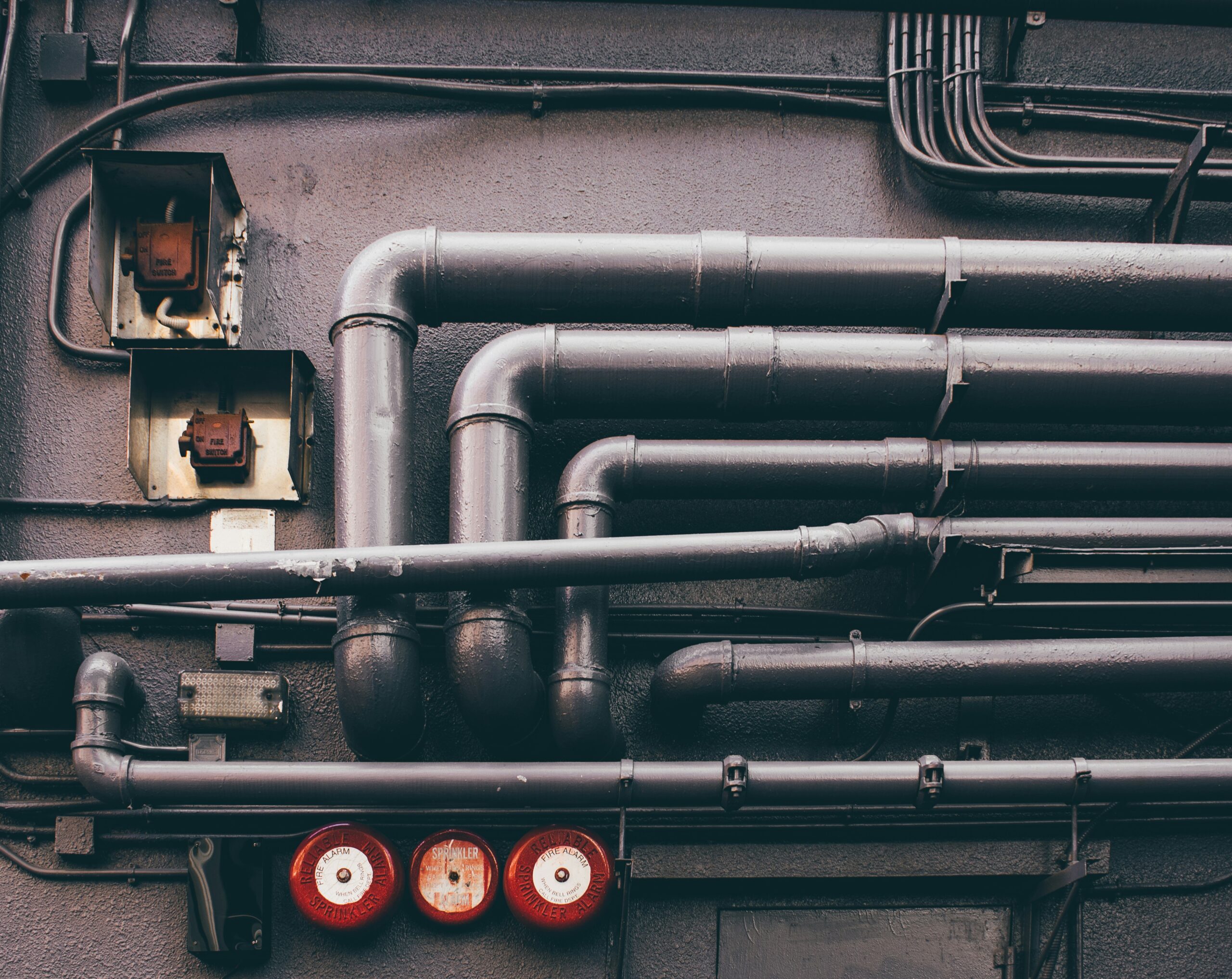 Pipes and valves on a wall, illustrating plumbing infrastructure relevant to emergency plumbing and boiler services in Draycott.